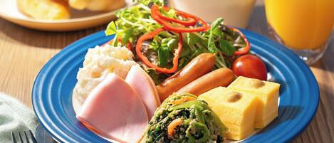 A plate with ham, cheese, vegetables, and a croissant.