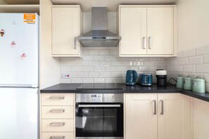 Fully equipped kitchen with a range hood, oven, and coffee maker.