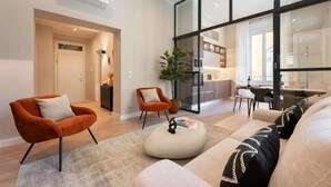 A modern living room with a sofa, two armchairs, a coffee table, and a dining area with a table and chairs.