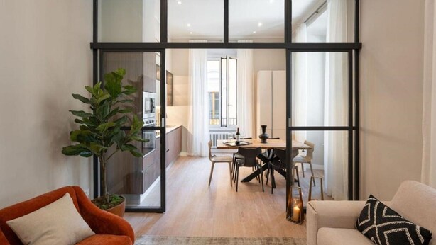 A modern living room with a large glass door leading to a dining area.
