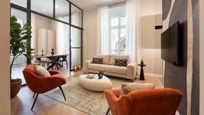 A modern living room with a sofa, two armchairs, a coffee table, and a dining area with a table and chairs.