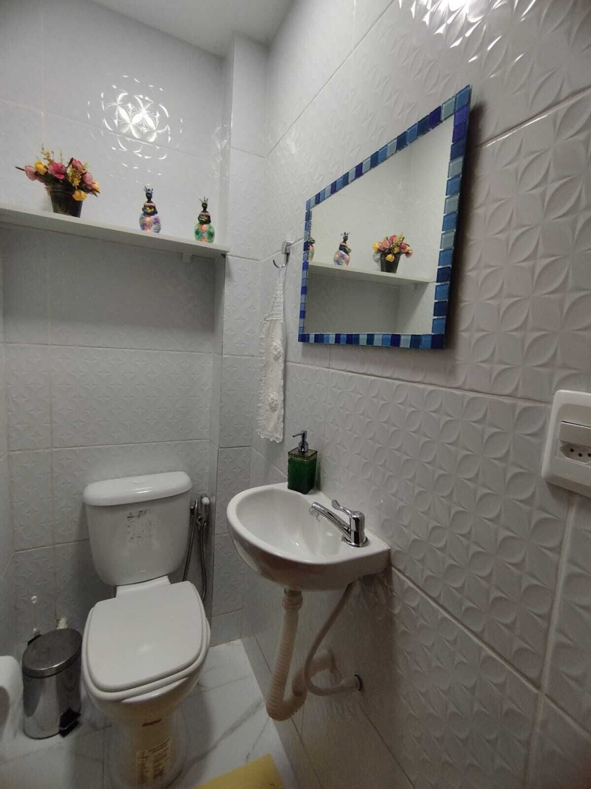 Un baño con inodoro, lavamanos y objetos decorativos en una estantería.
