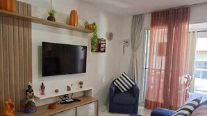 Un salon équipé d’un téléviseur, d’un canapé et d’un coin repas avec une table et des chaises.