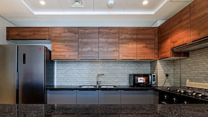 A modern kitchen with wooden cabinets, a stainless steel refrigerator, a microwave, and a gas stove.