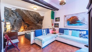 Une pièce chaleureuse avec un mur en pierre, un canapé, un fauteuil et un tableau.