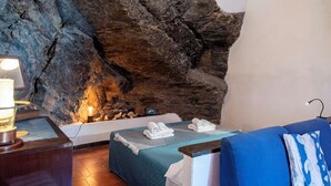 Une salle de spa avec un grand mur de pierres, une table de massage, un canapé bleu et une lampe.