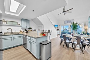A modern kitchen with a central island, light blue cabinets, and a ceiling fan.