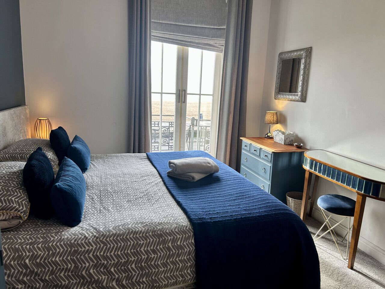 Ein Hotelzimmer mit Bett, Schreibtisch und Blick auf den Strand.