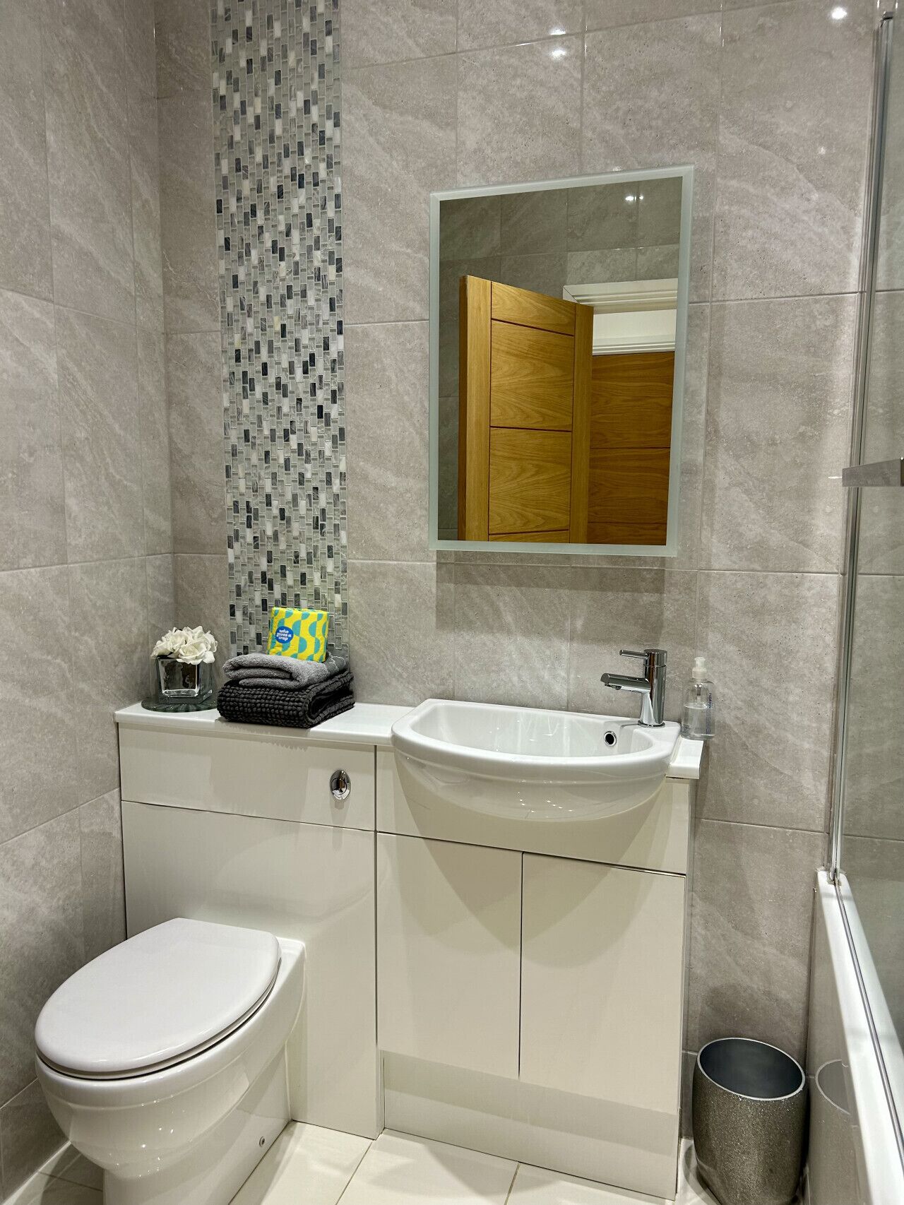 A modern bathroom with a white toilet, a sink, and a shower.