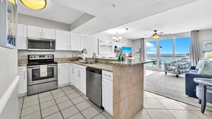 A modern kitchen with white cabinets, stainless steel appliances, and a large island. - ☀️ Pelican Beach 603 - Starfish by the Sea - Gulf Views ☀️ (Destin)