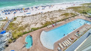 A beach resort with a swimming pool, beach umbrellas, and lounge chairs. - ☀️ Pelican Beach 603 - Starfish by the Sea - Gulf Views ☀️ (Destin)