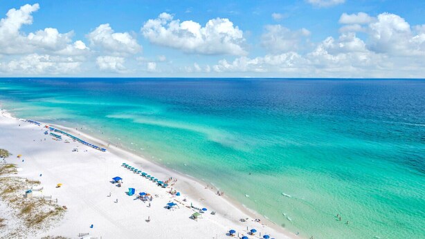 A beach with clear turquoise waters, white sand, and umbrellas. - ☀️ Pelican Beach 603 - Starfish by the Sea - Gulf Views ☀️ (Destin)