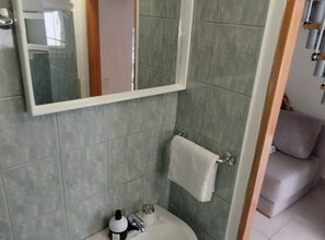 Ein Badezimmer mit Spiegel, Handtuch an einem Haken, Waschbecken und Toilette.