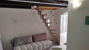 A modern living room with a sofa, a dining table with chairs, and a staircase with a wooden handrail. - Apartment Leo Povile (Novi Vinodolski)