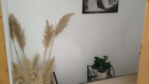 A wall with a black and white waterfall painting, pampas grass, and a potted plant. - Apartment Leo Povile (Novi Vinodolski)
