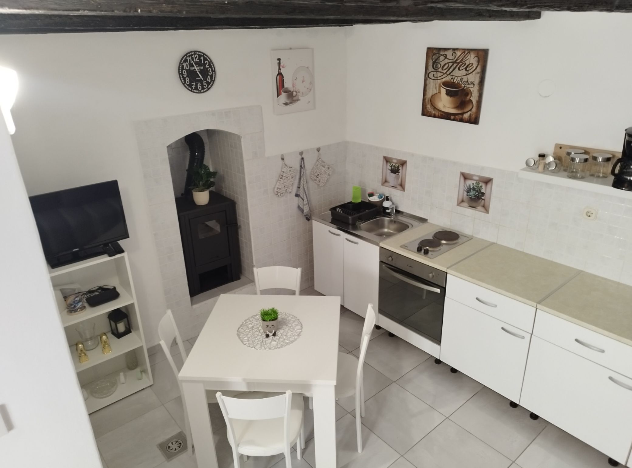 A compact kitchen with white cabinets, a sink, stove, and a dining area with a table and chairs.