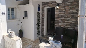A small outdoor patio area with a stone wall, a chair, and a table with decorative items. - Apartment Leo Povile (Novi Vinodolski)