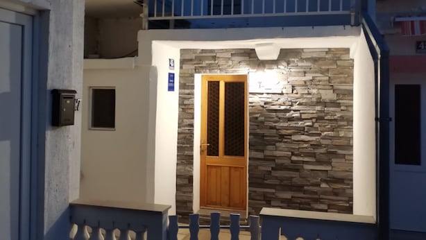 A residential building with a stone facade, a wooden door, and a balcony with a railing. - Apartment Leo Povile (Novi Vinodolski)