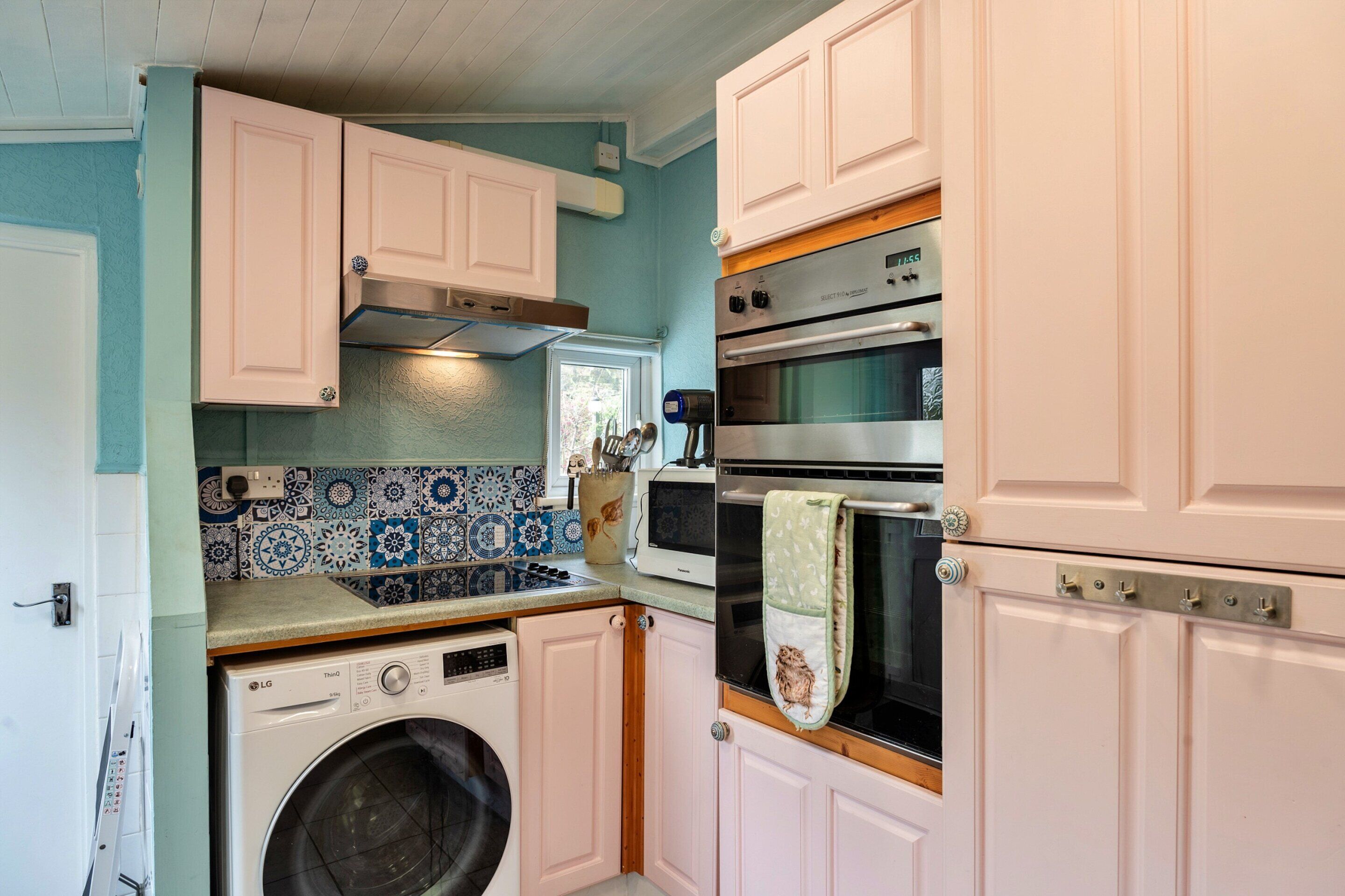 A compact kitchen with a washing machine, a microwave, and an oven.