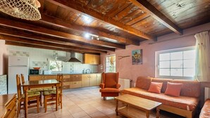 Un salon chaleureux avec un plafond en bois, un canapé, une table basse et un coin repas comprenant des chaises et une table.