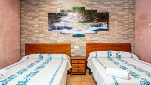 Une chambre d’hôtel avec deux lits, une tête de lit en bois, une table de chevet et un grand tableau représentant une cascade accroché au mur.