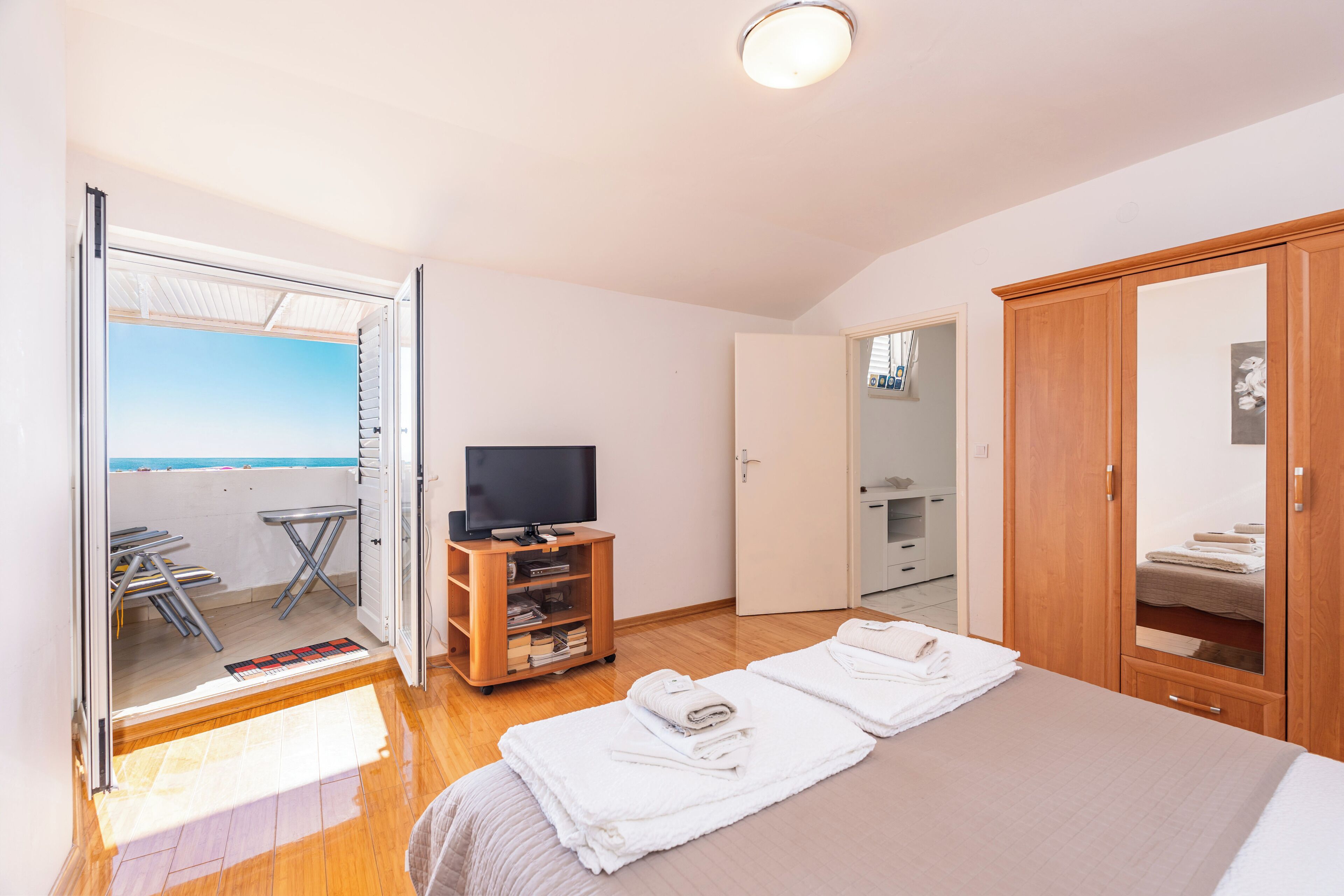 A bedroom with a bed, a television, a wardrobe, and a bathroom visible through an open door.