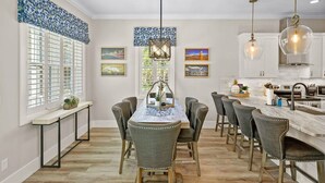 A modern kitchen with a central island, bar stools, and pendant lighting. - 2 Steps to Ice Plant Downtown St Aug Beach Club (St. Augustine)