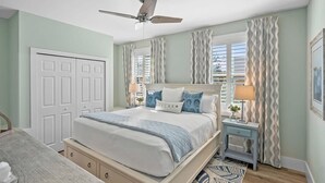 A bedroom with a bed, bedside tables, a ceiling fan, and a window with curtains. - 2 Steps to Ice Plant Downtown St Aug Beach Club (St. Augustine)