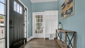 A hallway with a dark door, a white door, and a wooden console table with a lantern. - Pool and Hot Tub Walk to Ice Plant and Downtown (St. Augustine)