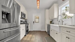 A modern kitchen with stainless steel appliances, white cabinetry, and a wooden floor. - Pool and Hot Tub Walk to Ice Plant and Downtown (St. Augustine)