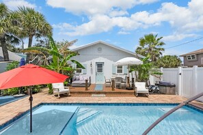 A backyard with a swimming pool, a white house, and outdoor furniture. - Mariners Cottage Steps to Sand Sparkling Pool (St. Augustine)