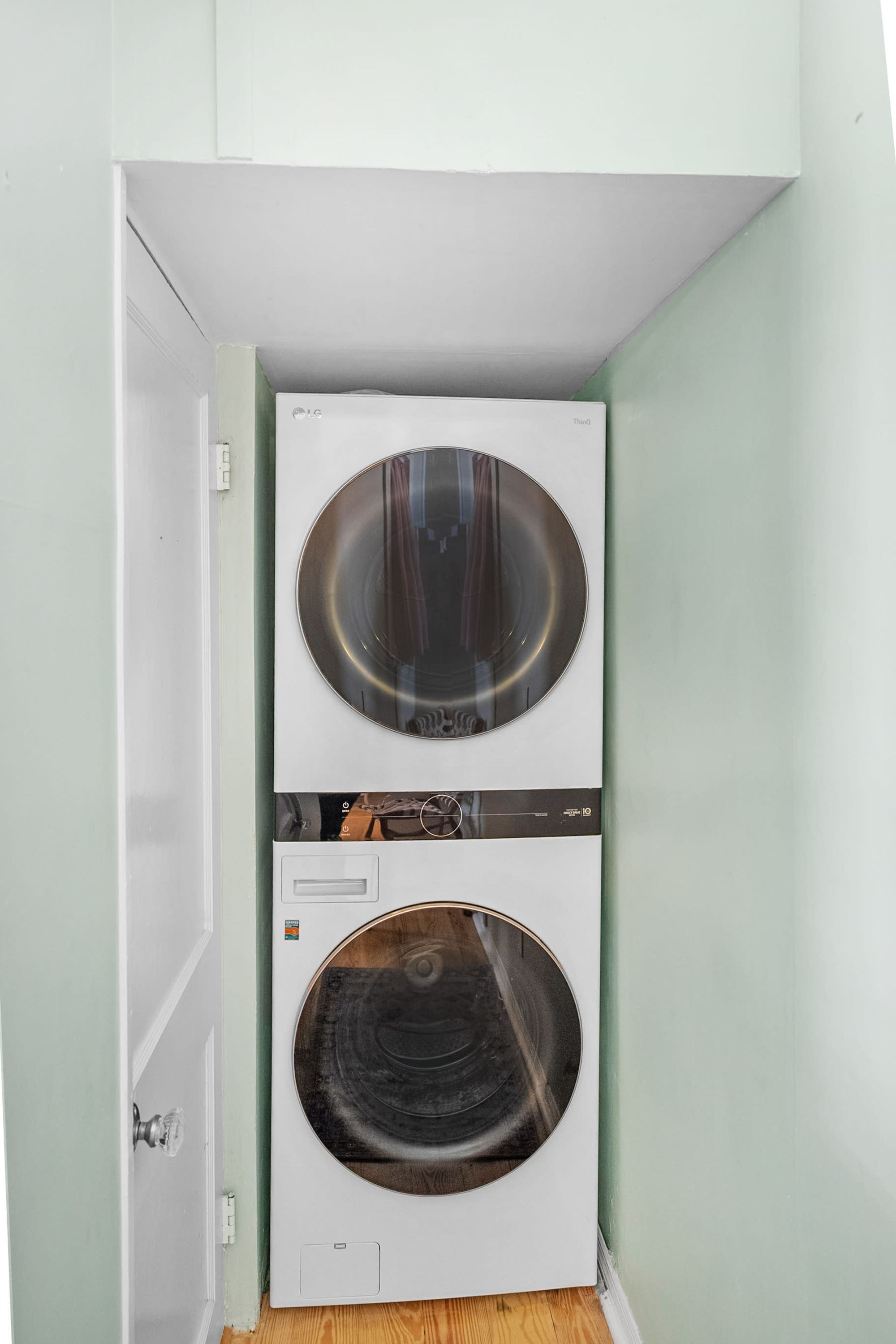 Une petite buanderie équipée de deux machines à laver à chargement frontal superposées.