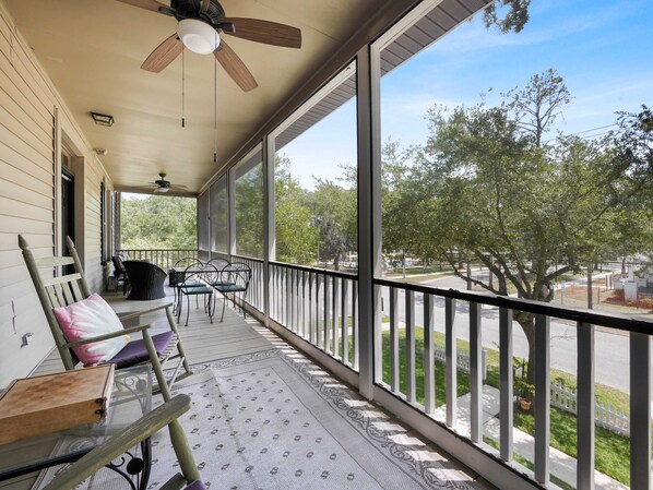 A covered porch with a ceiling fan, a view of the street, and outdoor furniture.