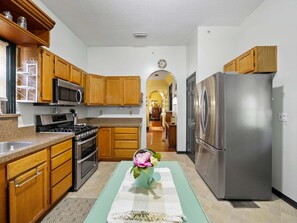 A kitchen with wooden cabinets, a stainless steel refrigerator, and a microwave.