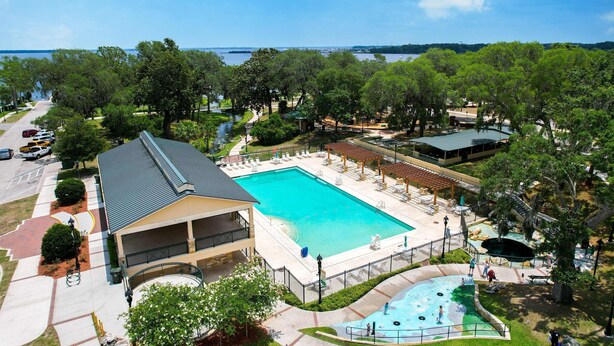 A large swimming pool with a covered area, surrounded by trees and a view of the water.