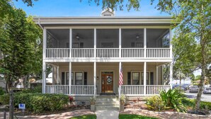 A two-story house with a front porch, a flag, and a well-maintained lawn.