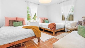 Une chambre avec deux lits, une fenêtre et un luminaire suspendu.