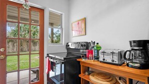 Une cuisine compacte avec un fourneau noir, un grille-pain et une machine à café placés sur une étagère en bois.