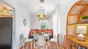 Un espace repas avec une table ronde, des chaises blanches et un luminaire central.