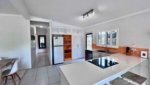 Una cocina moderna con armarios blancos, horno empotrado y una isla grande con encimera negra.