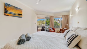 Une chambre d’hôtel avec un lit, un balcon donnant sur un beau paysage et un tableau accroché au mur.