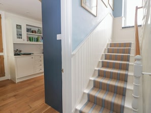 A staircase with striped carpet, a wooden handrail, and white walls. - Ty Clyd (Newport)