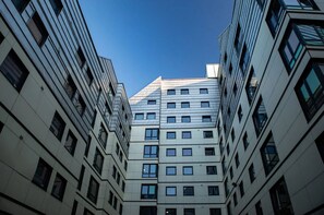 A modern multi-story building with a symmetrical facade, large windows, and a clear sky. - Burley Road - Campus Accommodation (Leeds)