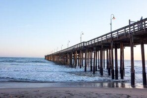 A pier extending into the ocean with a wooden walkway and street lamps.