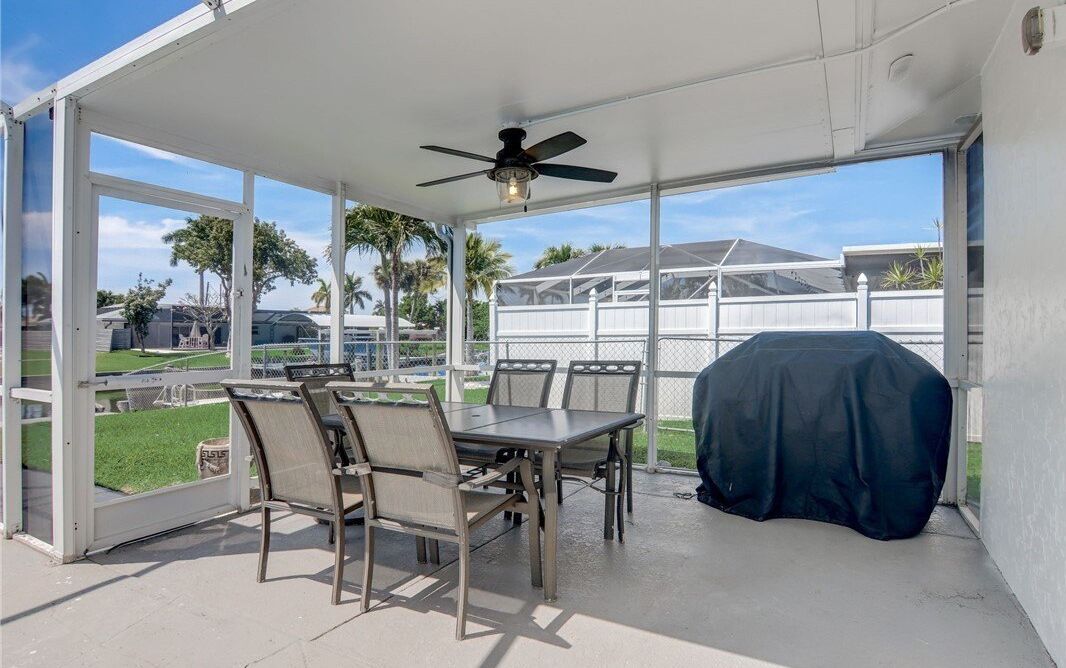 A covered patio with a table and chairs, a ceiling fan, and a barbecue grill.