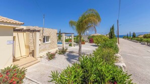 A residential area with a stone building, a small garden, and a clear view of the sea.