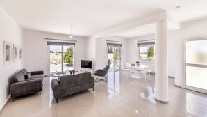 A spacious living area with a sofa, a TV, and a dining table with chairs.