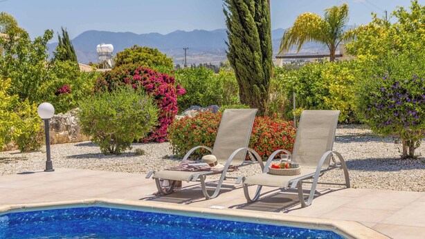 A pool area with three lounge chairs and a lamp post.