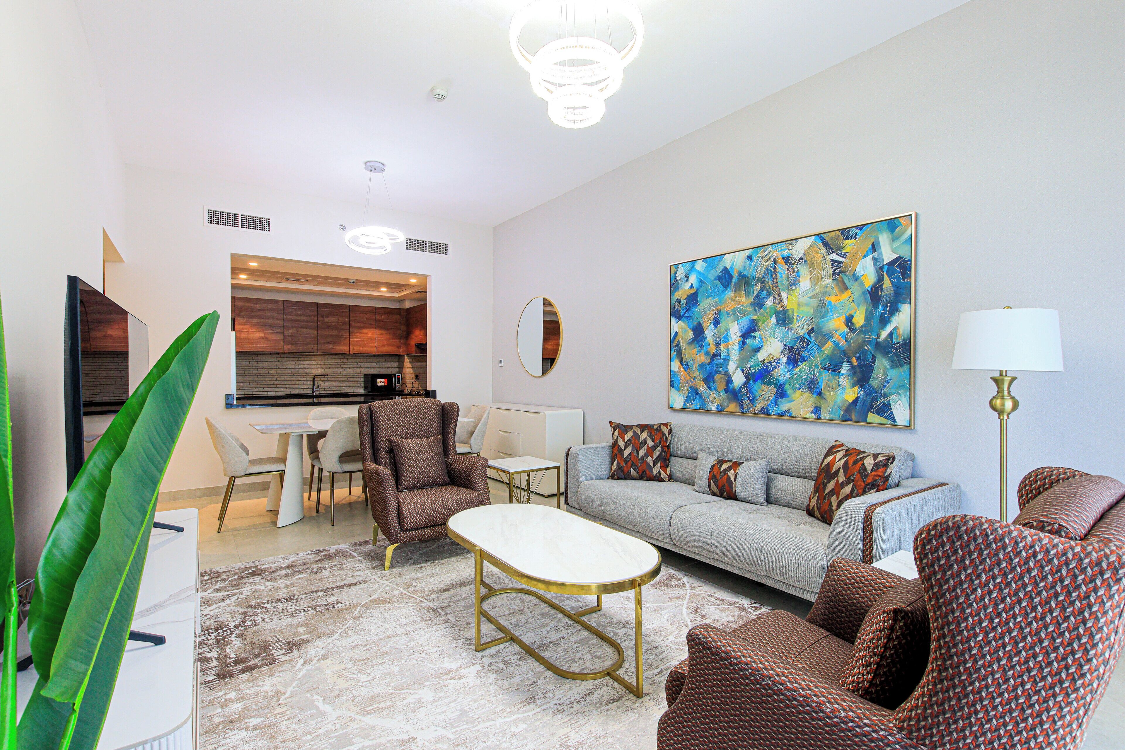 A modern living room with a sofa, armchairs, a coffee table, and a dining area with a table and chairs.