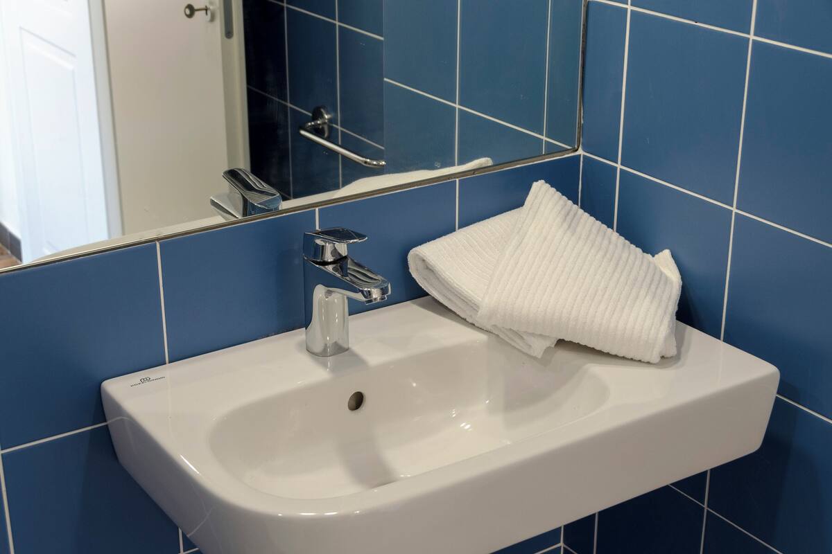 Ein Badezimmer mit einem weißen Waschbecken, einem Spiegel und einem Handtuch.